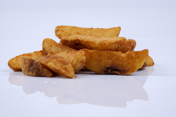 Potato wedges are wedges of potatoes, often large and unpeeled isolated on white