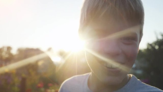 Portrait of a smiles handsome boy on a background of sunlight hand beckoning to him at sunset time in slowmotion. 1920x1080