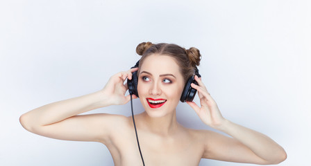 Young pretty woman trendy makeup bright red lips bun hairstyle bare shoulders act the ape with big dj headphones on white studio background