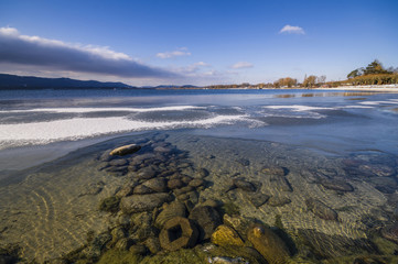 Fototapeta na wymiar Sonnige Winterlandschaft am Bodenseeufer mit Steinen im Wasser 