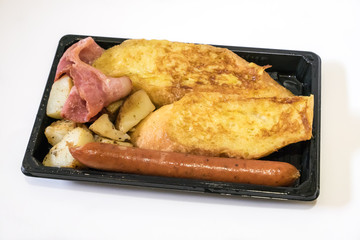 The close up of delicious breakfast set on black plastic tray. (becon, sausage, potato, omelette) 