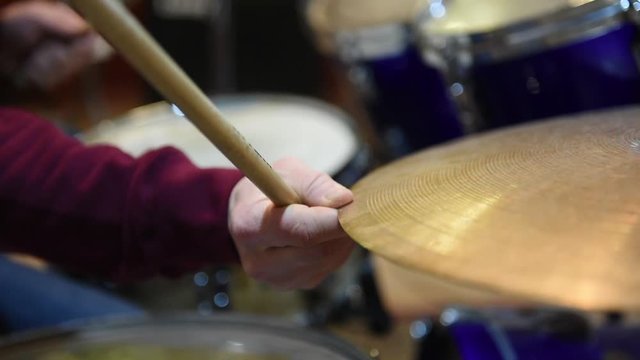 Drummer playing instrument. Closeup on cymbal and final hit with hand stopping dish