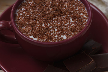 Milk chocolate in a cup on a saucer on a wooden background. Clos