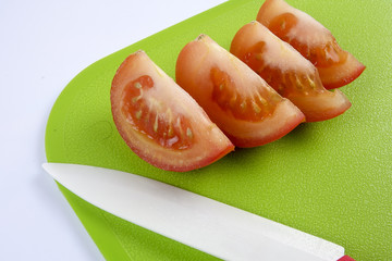 Sliced tomato on green chopping board.