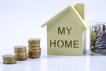 Wooden house model with pile of coin and calculator. House finance concept.