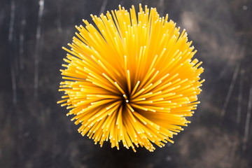 Bundle of uncooked spaghetti top view flower like shape, on black vintage background
