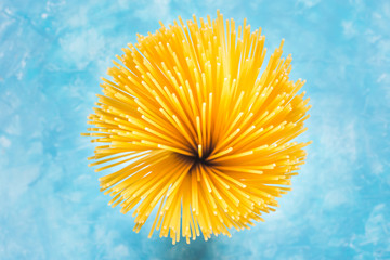 Bundle of uncooked spaghetti top view flower like shape, on blue and white background