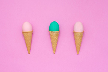 three eggs in waffle cones on a pink background.