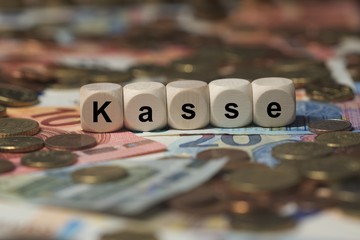 kasse - Holzwürfel mit Buchstaben im Hintergrund mit Geld, Geldscheine