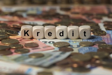 kredit - Holzwürfel mit Buchstaben im Hintergrund mit Geld, Geldscheine
