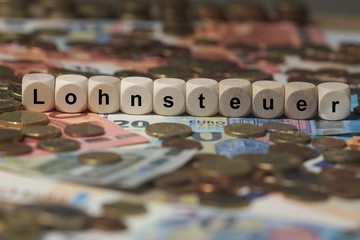 lohnsteuer - Holzwürfel mit Buchstaben im Hintergrund mit Geld, Geldscheine