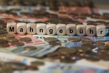 mahngebühr - Holzwürfel mit Buchstaben im Hintergrund mit Geld, Geldscheine