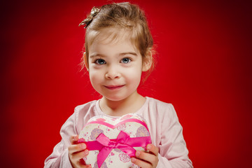 small and pretty girl holding a gift in the shape of heart