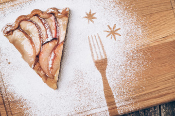 A piece of sliced apple pie with cinnamon on vintage wooden background texture. Top view.