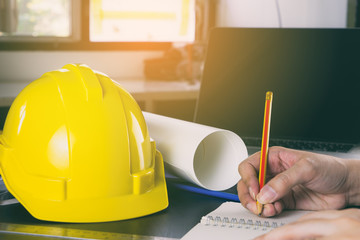 Engineer is working on construction plan on his table.