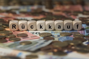 rückkauf - Holzwürfel mit Buchstaben im Hintergrund mit Geld, Geldscheine
