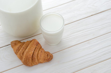 Glass of milk and a croissant on the table.
