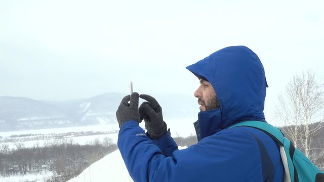 Traveler With a Beard Using Smartphone On Mountain. Caucasian Men in Jacket looking for a GPS Signal. Mountaineer Winter Mobile Communications.Adventure Expedition Man Talking Cell Men Call Accident