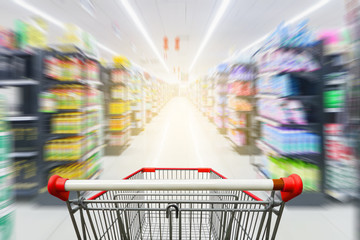 Supermarket aisle with empty red shopping cart - obrazy, fototapety, plakaty