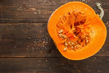 Foto op Plexiglas Cut half of orange pumpkin on wood free space flat lay. Top view on rustic wooden table with cutaway fresh squash. Seasonal, dieting, vegetarian cuisine concept. Free space for your text. © Photodrive