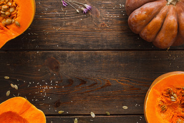 Fresh cut pumpkin frame on wood free space. Top view on rustic wooden table with orange squash pieces in corners. Organic food ingredients, vegetarian cuisine, seasonal menu concept