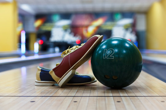 Bowling ball and shoes on lane background