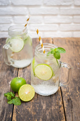 Homemade lemonade drink with fresh lime in glass on old wooden background
