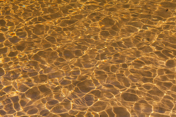 Golden sand ripples through wave of water Abstract background