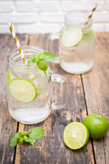 Homemade lemonade drink with fresh lime in glass on old wooden background