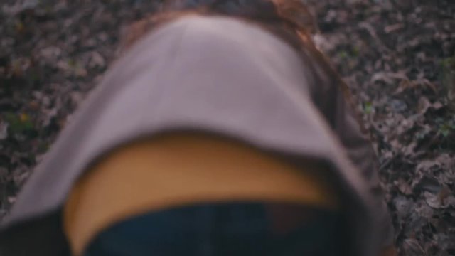 Small teenage girl with long brunette hair and stylish look. Scared little girl running in the forest, she looks around terrified as something is following her, falls down, rushes to get up and run.