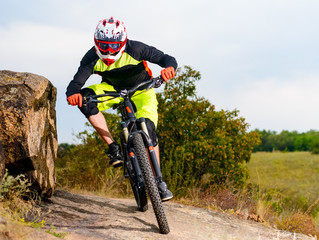 Naklejka premium Professional Cyclist Riding the Bike at the Rocky Trail. Extreme Sport Concept. Space for Text.