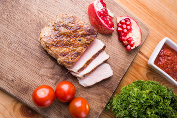 Sliced grilled steak on chopping board with tomatoes and spices