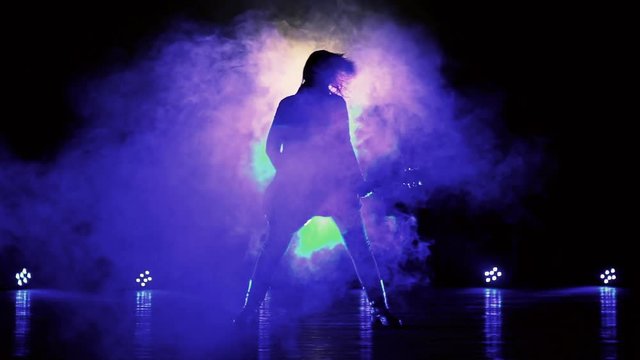 Silhouette of a girl with a guitar in the smoke. Strobe lights, smoke machines. Concert rock band,  guitar. Music video, heavy metal or rock group. Slow motion. 