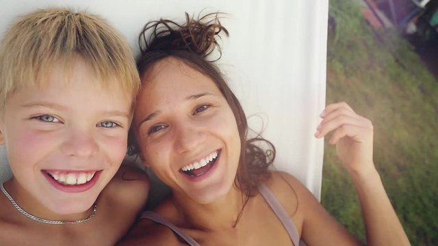 Happy beautiful mother and her son have a rest in a garden in hammock in slowmotion. 1920x1080
