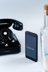 Vintage, modern phone, and message in a bottle, isolated on a gray background.