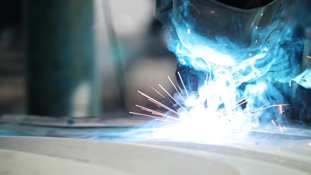 Industrial concept: worker in helmet repair detail in car auto service, close up