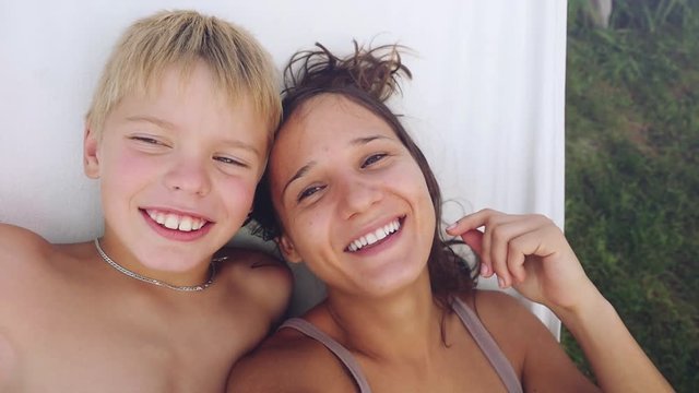 Happy pretty mother and her handsome son have a rest in a garden in hammock in slowmotion. 1920x1080