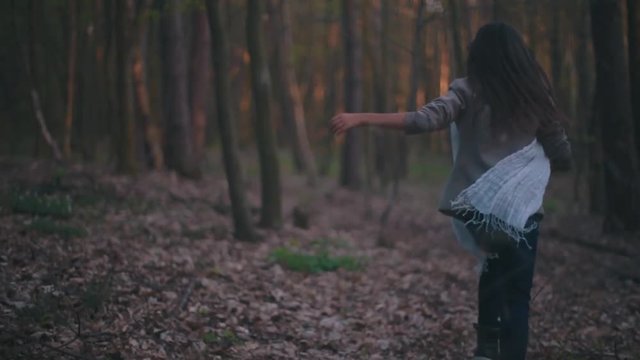 Little lost girl with a bright scarf running through the dark forest, she is frightened and lonely, she falls down, gets up and continues running. Forest mysteries, danger. Dark deserted wood.
