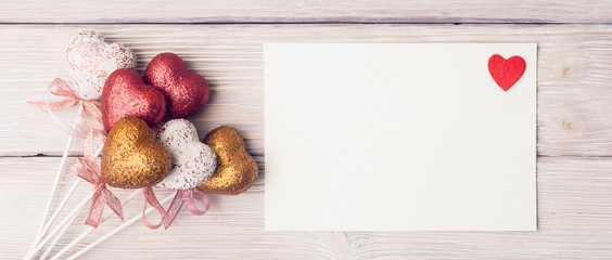 Blank white paper sheet with Valentines hearts over light wooden