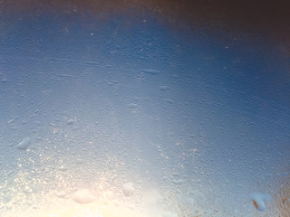 Blurry water drops on sunshine ffrozen window glass background
