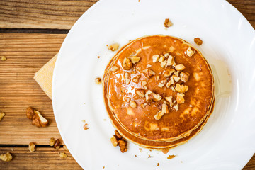 Pancakes with honey and walnuts on rustic wooden background
