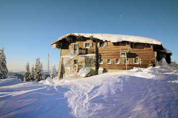 Mountain hut covered with snow in beautiful sunshine day.