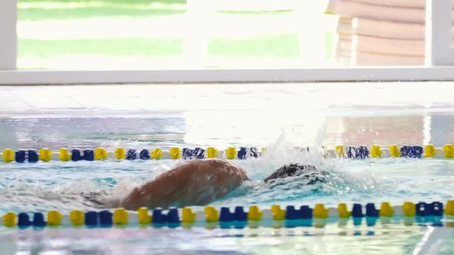 Slowmotion - the sportsman swimming breaststroke in the swimming pool