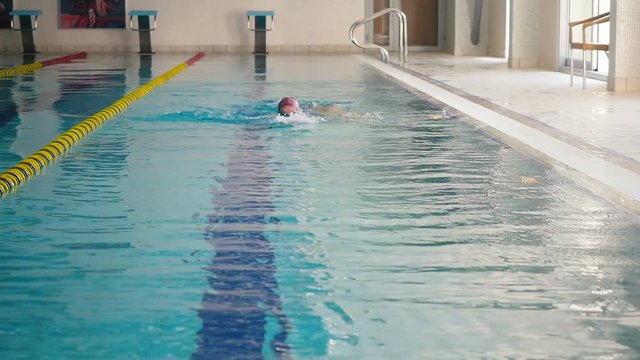 Little girl in gogles swimming crawl in the swimming pool