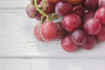 Red grapes over the white wooden board.