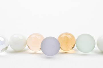 Glass marble row in pastel colors, on white background