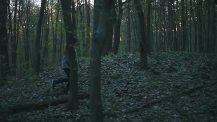 Little European girl with a long hair, brown jacket, black pants, sneakers and bright blue scarf. A scared little child is running through the dark deserted forest. Nightmare, loneliness.