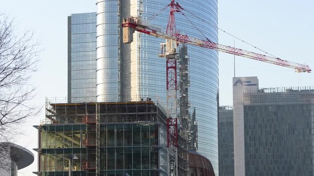 Uomini al lavoro in cantiere con gru di sollevamento lavorano ad un palazzo a pi&ugrave; piani in Milano Centro