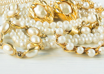 Woman's Jewelry. Vintage jewelry background. Beautiful gold and pearl necklaces, bracelets and earrings on white wood. Flat lay, closeup