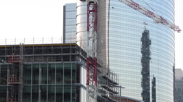 Uomini al lavoro in cantiere con gru di sollevamento lavorano ad un palazzo a pi&ugrave; piani in Milano Centro